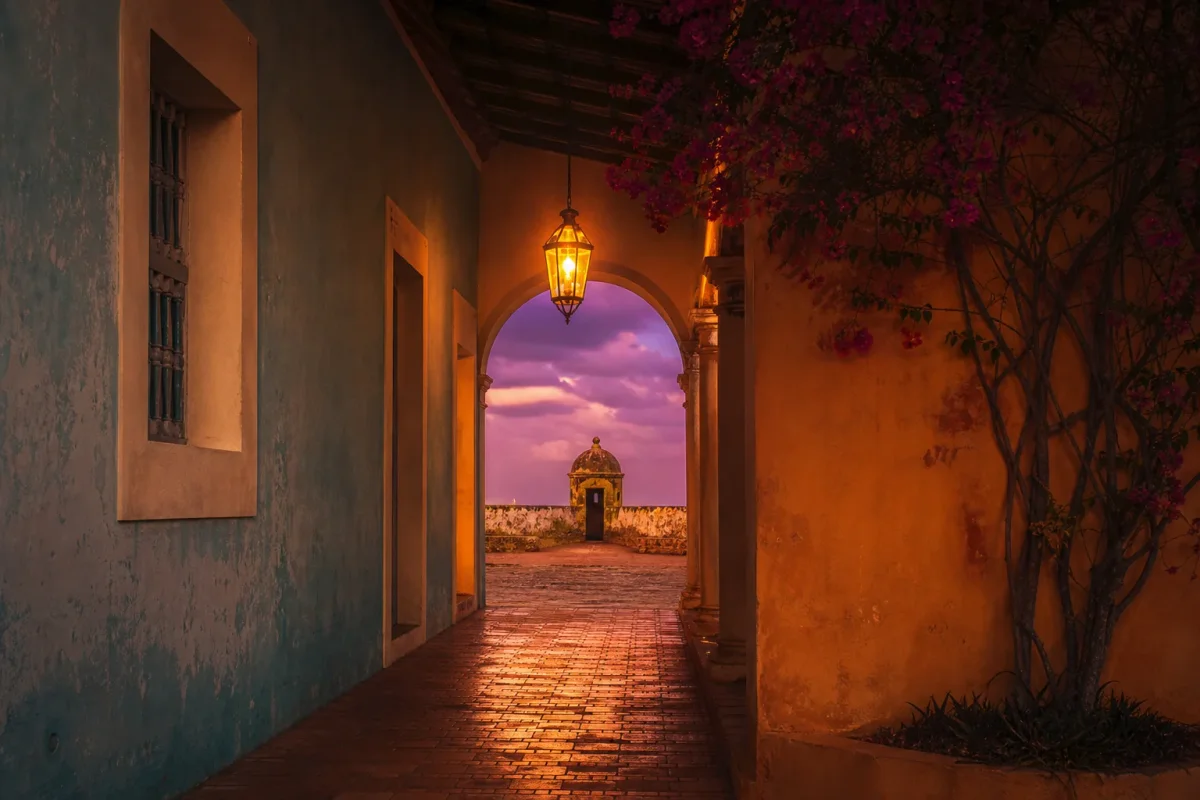 Un farol encendido colgando en un pasillo colonial al atardecer